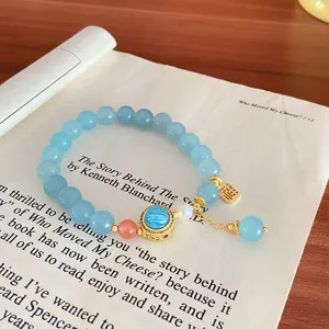 Light blue natural stone bracelet detail shot with gold charms and cute beaded accessories.