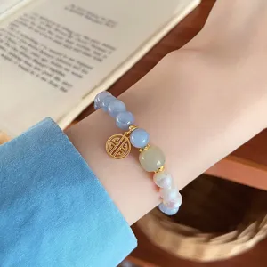 Detailed shot of a stylish natural stone and pearl beaded bracelet with a cute gold charm.