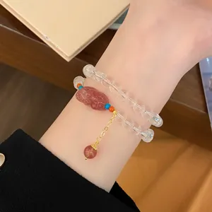 Gros plan sur le bracelet de perles de cristal avec charm pixie rouge et chaîne dorée.