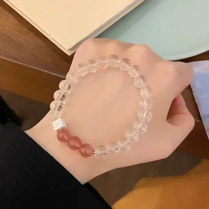 Gros plan d'un bracelet de perles en cristal blanc transparent doux avec pierre rose et cube argent.