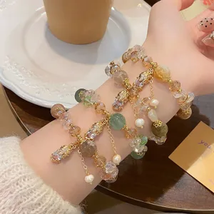Close-up detail of multi-layer rutilated quartz and sunstone bracelets with lucky Pixiu charms.