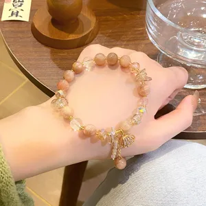 Gros plan détail du bracelet de perles en pierre naturelle et cristal doux avec pendentif coquillage.