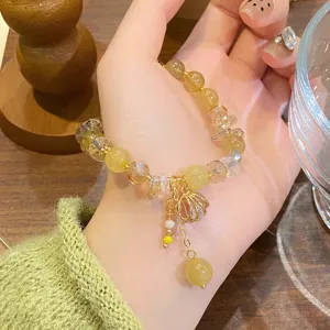 Gros plan sur le bracelet de perles en cristal jaune naturel avec pendentif coquillage.
