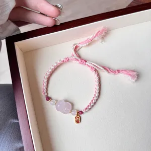 Delicate braided pink crystal bracelet with lucky charm pendant, sweet adjustable design.