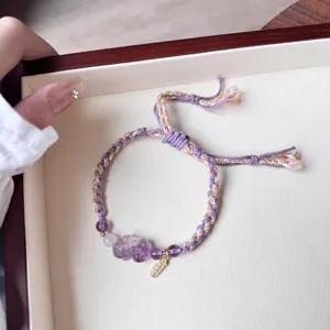 Close-up of the braided purple and beige crystal bracelet featuring an amethyst Pixiu charm.
