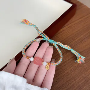 Detailed view of the Tibetan ethnic braided bracelet with pink crystal and golden Fu charm.
