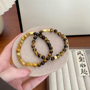 Nahaufnahme der Details von natürlichen Tigerauge Edelstein Armbändern mit goldenen Anhängern.