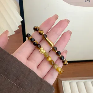 Nahaufnahme Detail von gelben Tigerauge Perlen Armband mit goldenem Fisch Anhänger.