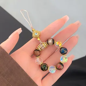 Close-up detail of colorful multi-gemstone phone charm with gold metal beads and elegant strap.