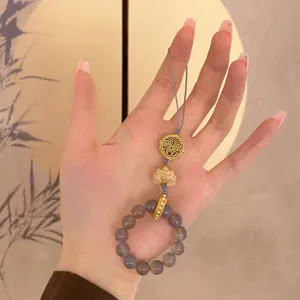 Exquisite beaded phone charm detail, featuring grey agate, carved lotus wood, and golden totem.