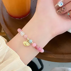 Detail shot of sweet macaron colored jade bracelet with golden ruyi lock pendant on wrist.