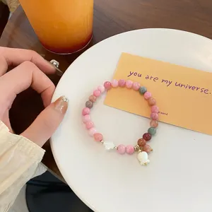 Close-up of colorful beaded bracelet with mother-of-pearl flower charm and tulip pendant.