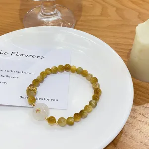 Yellow crystal and golden tiger's eye beaded bracelet with white jadeite and floral charm detail.