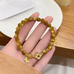 Detailed view of yellow crystal tiger eye stone bead bracelet with chic flower and butterfly charms.