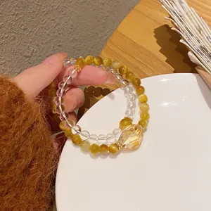 Close-up detail of double-strand crystal and yellow tiger eye bead bracelet with lucky ingot.