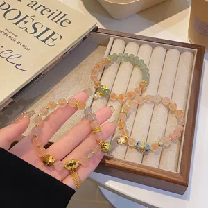 Gros plan détaillé de bracelets de perles en agate avec des charms dorés sur un plateau.