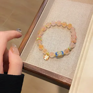 Gros plan détaillé du bracelet de perles en agate rose avec breloque chat porte-bonheur.