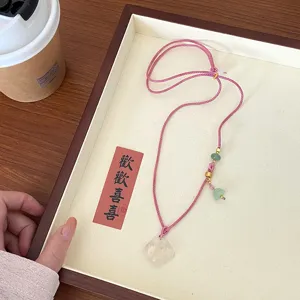 Delicate natural white agate ruyi necklace detail, featuring pink cord and green bead charms.