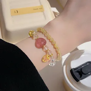 Close-up detail of double-layer beaded bracelet featuring crystal and strawberry heart charms.