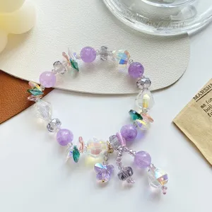 Gros plan détaillé du bracelet de perles en cristal violet scintillant avec pendentif papillon.