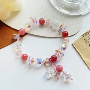 Gros plan sur le bracelet en cristal rose, perles à facettes étincelantes et papillon charmant.