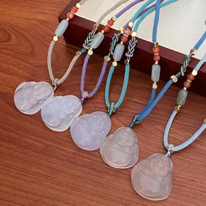 Detailed shot of woven sweater chains featuring carved Buddha pendants and colorful braided cords.