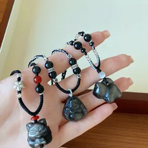 Gros plan de pendentifs en obsidienne avec des motifs de renard et de Bouddha sur des cordons.