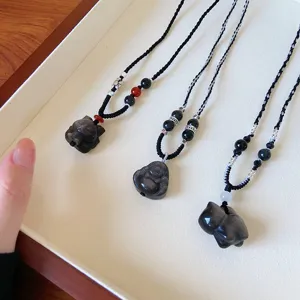 Vue détaillée de colliers pendentifs en obsidienne naturelle avec des cordes tressées.
