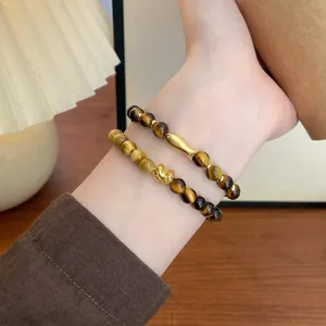Nahaufnahme von doppelten gelben Tigerauge Perlenarmbändern mit goldenen Koi-Fisch-Charms.