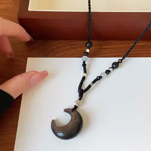 Vue détaillée du collier pendentif lune en obsidienne noire avec cordon tressé.