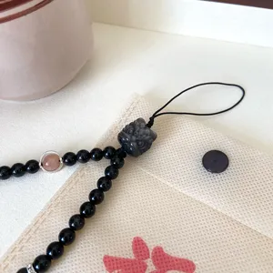 Gros plan d'un bijou de telephone en pierre naturelle style chinois avec perle sculptee.