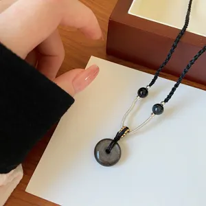 Gros plan du pendentif en obsidienne naturelle avec chaîne tressée élégante pour un style unique.