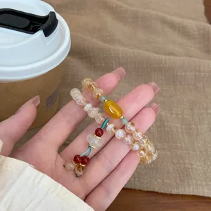 Gros plan sur le bracelet double couche en cristal naturel avec perles et charmant gland.
