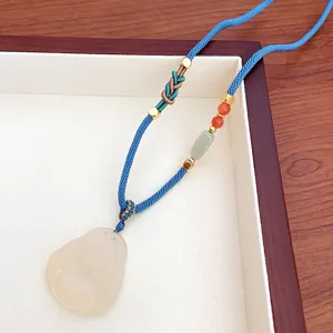 Chinese style natural white agate Buddha pendant necklace with blue braided cord detail.