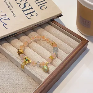 Gros plan détaillé du bracelet de perles en agate translucide avec pendentif cadenas doré.