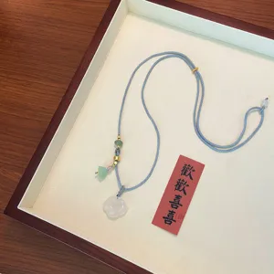 Detail view of white agate ruyi necklace pendant with blue cord and multi-gem accents.