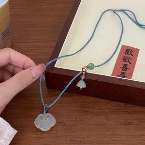 Chinese style white agate ruyi pendant necklace featuring blue braided rope and elegant beads.
