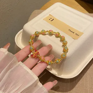 Gros plan detaille du bracelet de perles dorees emaille cloisonne avec papillon rouge.