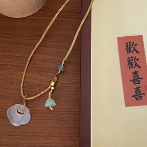 Close-up detail shot of a vintage Chinese style white agate ruyi pendant necklace with beads.