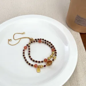 Double-layer crystal beaded bracelet featuring lucky charm and adjustable gold chain.