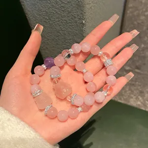 Close-up details of natural rose quartz beaded bracelet with cute crystal fox pendant and gems.