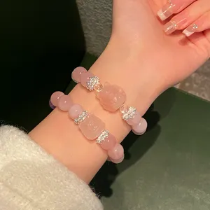 Close-up detail of natural pink crystal bracelet with fox charm and silver crown beads.