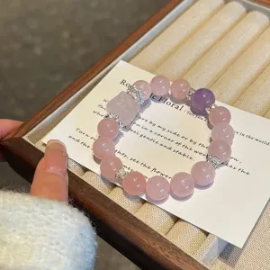 Natural rose quartz crystal beaded bracelet detail showcasing carved fox charm and pink beads.