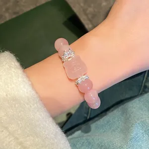 Delicate rose quartz crystal bracelet detail, featuring sparkling silver spacers and cute pendant.