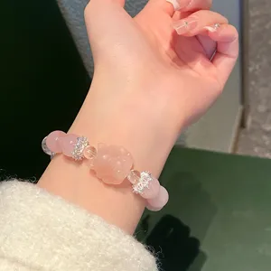 Detailed close-up of natural rose quartz beaded bracelet with carved fox mascot and silver spacers.