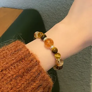 Gros plan détaillé d'un bracelet en cristal de citrine naturelle et œil de tigre au poignet.
