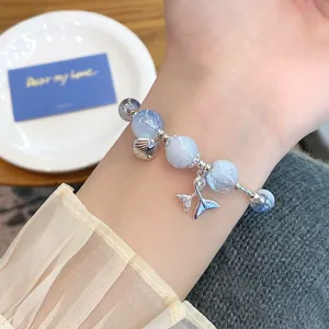 Close-up detail of the blue cracked crystal bead bracelet featuring a delicate shell charm.