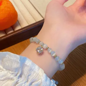 Gros plan sur le bracelet de perles en pierre d'œil de chat avec pendentif en cristal.