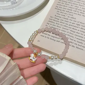 Detailed shot of a sweet pink crystal pearl bracelet with a rocking horse pendant on book.