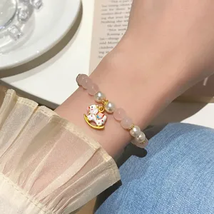 Detail shot of a sweet pink crystal and pearl bracelet featuring a cute rocking horse charm.